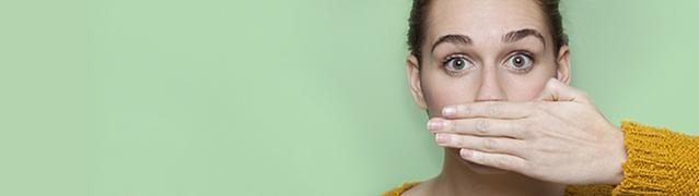 woman afraid of bad breath covering up mouth with her hand