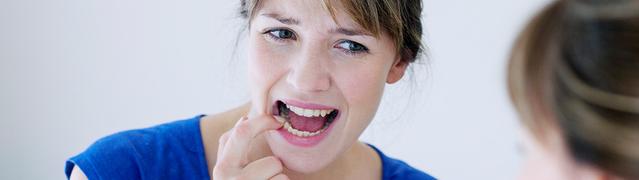 woman inspecting her teeth in the mirror wanting to prevent early gum disease 