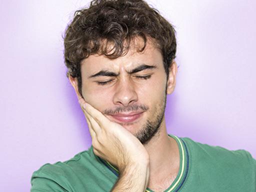 younger man holding cheek suffering from cavity pain