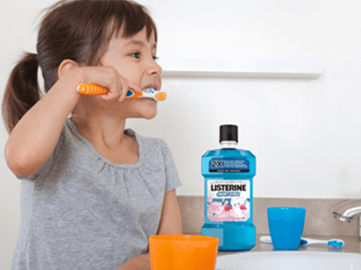 little girl brushing her teeth and using Listerine mouthwash